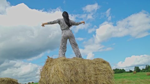 Girl dancing in stylish suit with animal print on top of hay bale, feeling Liberty at Countryside