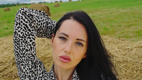 lose up of Woman’s Face, Girl opening her Beautiful blue Eyes. Sexy Brunette woman sensually posing on hay in rural areas