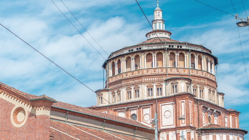Santa Maria delle Grazie timelapse with blue cloudy sky. Milan, Italy. People walking around. Traffic on the road. This church and the adjacent Dominican convent were built during the 15th century.
