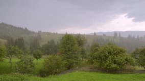 Summer downpour over the green summer mountain hills. Rainy weather. Scenic footage of forces of nature. Cinematic shot. Filmed in Full HD 1080p video. Slow motion clip 240 fps. Beauty of earth.