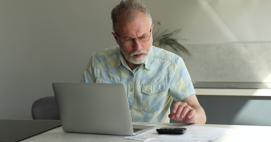 Senior man use laptop and calculator, calculates family budget feels angry, upset due to high taxes, huge household utilities need to pay. Bankrupt, insufficient old-age pension to pay bills concept Royalty-Free Stock Footage #1088175979