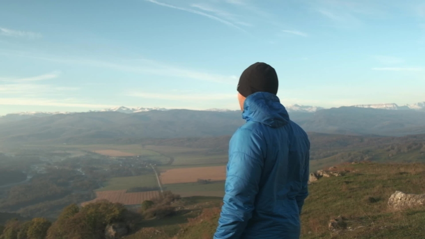 a guy looks around in the mountains, a man looks at a beautiful view
