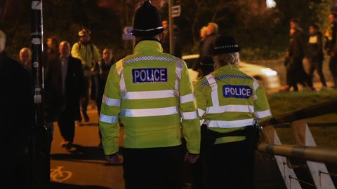 Norwich, Norfolk, United Kingdom, March 10, 2022. Two police officers yellow high visibility jackets at night watch  Chelsea football supporters near Norwich City Football Club Carrow Road stadium.