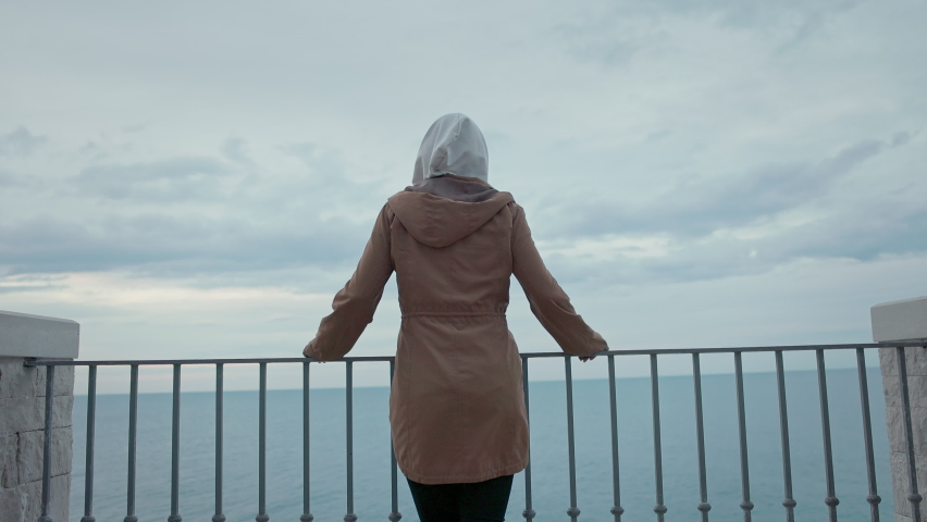 Girl In Hood Stands Near Bridge. Face Is Not Visible.