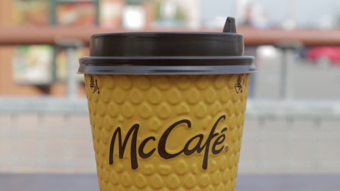 Yellow cardboard coffee cup from McDonald's. Mc Cafe paper glass drink. One coffee cup on the table with hot tea or coffee. Menu in a fast food restaurant. Ukraine, Kiev - September 12, 2021.