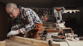 Carpenter working on a Wooden plank with a File in his Workshop. High quality 4k footage