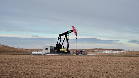 Milo, Alberta - March 12, 2022: Oil pump jacks in Alberta, Canada operating on a winter evening. 