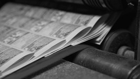 Printed paper newspapers move along the conveyor one after another. Black and white video. Move printed publications, newspapers. Media, article, daily news, print edition, journalism, politics