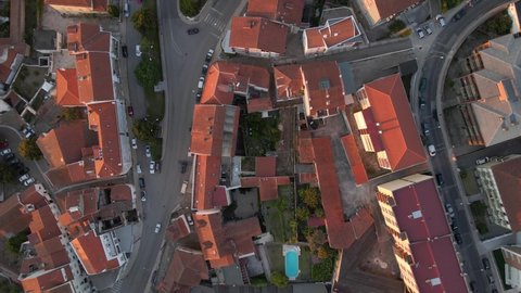 Aerial top view of red roof tops during sunset in the city of Coimbra, Portugal - Drone overhead shot - Golden hour