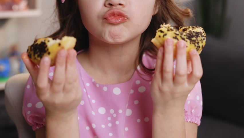 Close up of female mouth eating vegan doughnut with chocolate banana icing. Woman is eating two donuts at the same time. Sweet addiction concept