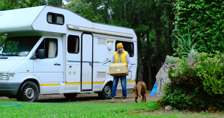 Family vacation travel RV, holiday trip in motorhome, Caravan car Vacation. a man in a yellow vest with a box in his hands. travel man preparing to travel by caravan car with his beloved dog Royalty-Free Stock Footage #1088186847