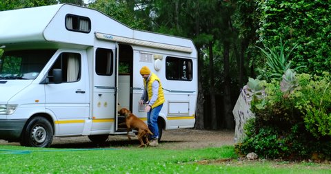Family vacation travel RV, holiday trip in motorhome, Caravan car Vacation. a man in a yellow vest with a box in his hands. travel man preparing to travel by caravan car with his beloved dog
