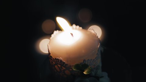 A burning candle in a dark room was taken in close-up.