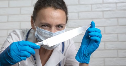 Crazy doctor with knife. A view of mad doctor in uniform with big medical knife in hands.