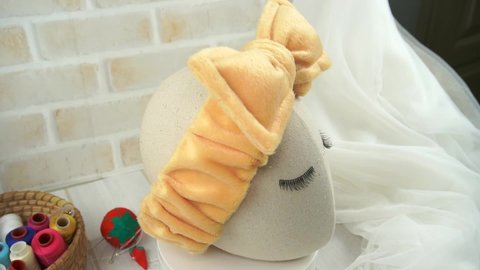 A mannequin wearing headband with bow pattern made out of fur fabric in soft brown color, great as hair accessories for washing face.