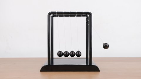 Slow motion, Newton's Cradle metal balls on wooden desk, swinging metal balls, Close up.