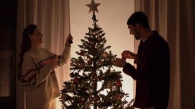 winter holidays and people concept - happy couple decorating christmas tree at home in evening - Powered by Shutterstock - Get 15% off with code: PIKWIZARD15