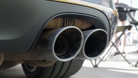 Bottom view of the exhaust system of a new luxury car. Panoramic view. Close-up of a dual exhaust pipe to remove harmful substances from engine exhaust and reduce vehicle noise.