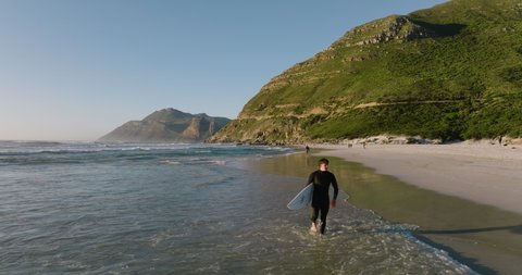 Aerial view of a surfer holding his surfboard walking along the surf, Cape Town, South Africa