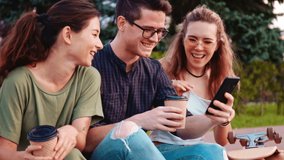 Happy smiling teenage friends laughing outside at something in smartphone or mobile phone. Three young multiracial people spending time together. Friendship, communication, youth and lifestyle concept - Powered by Shutterstock - Get 15% off with code: PIKWIZARD15