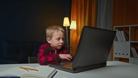 Little child boy following a preschool class using distance learning and shakes his head negatively