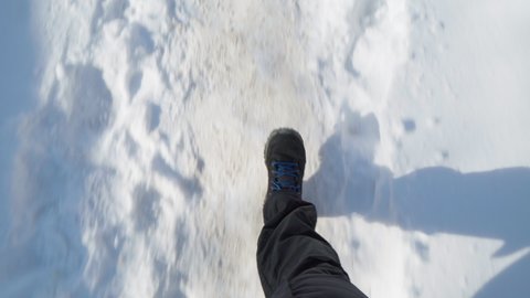 legs of a man in black boots and jeans walking in the snow in winter. Pov video
