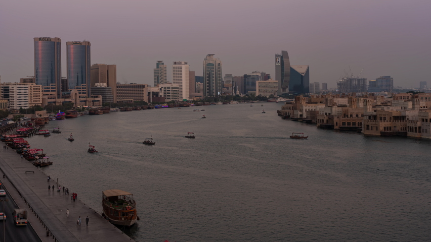 Dubai, United Arab Emirates - October 14 2021: Day to night time lapse of Dubai Creek with the small water taxies crossing the canal