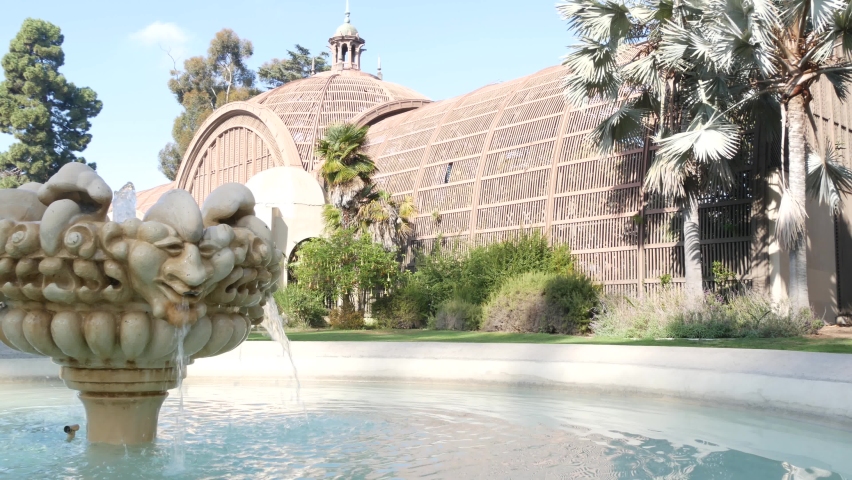 Botanical building exterior or facade in garden, green grass lawn, palm trees and fountain. Spanish colonial revival architecture in Balboa Park, San Diego, California USA. Wooden cupola or dome.