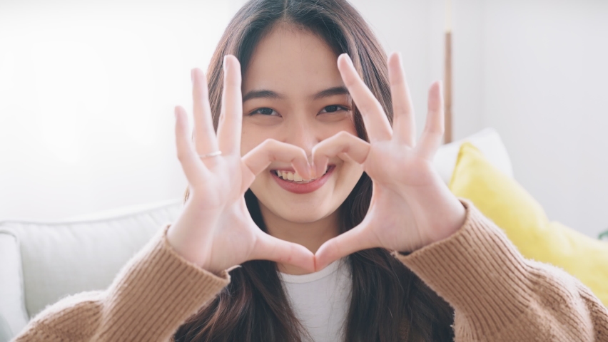 Close up of happy young asian woman smiling and showing hands sign heart shape looking at camera. Healthy heart health life insurance, love and charity, voluntary social work. Royalty-Free Stock Footage #1088212963