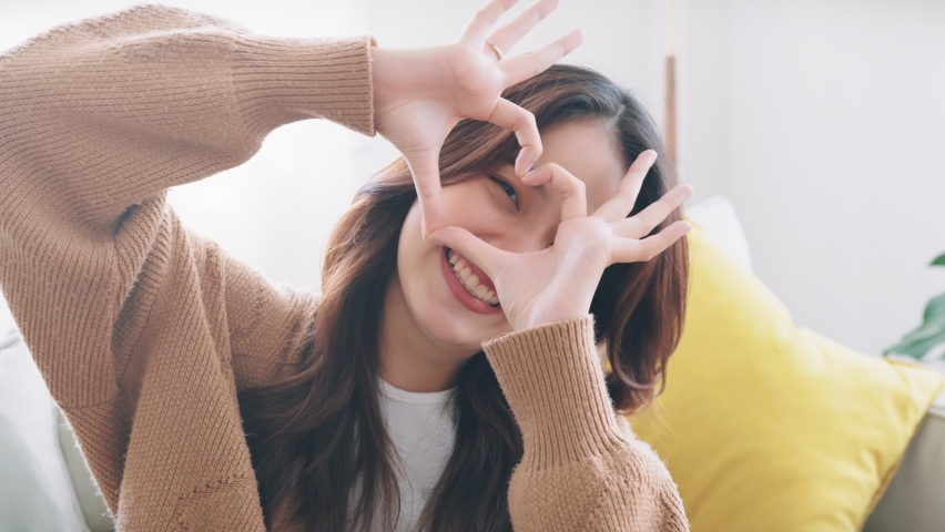 Close up of happy young asian woman smiling and showing hands sign heart shape looking at camera. Healthy heart health life insurance, love and charity, voluntary social work. | Shutterstock HD Video #1088212963