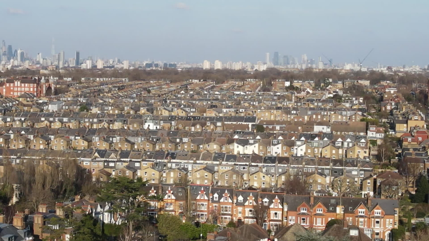 London- Aerial view of terraced houses in south west London with panning across the city of London financial district centred on the horizon 