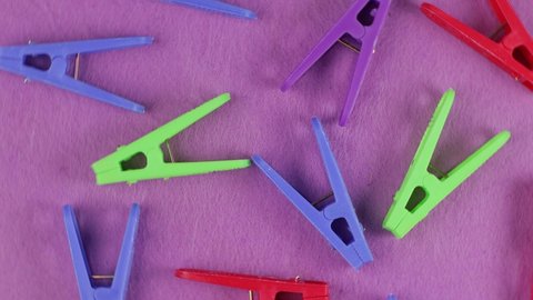 Colored clothespins on a lilac background, top view, close-up, bright backdrop.