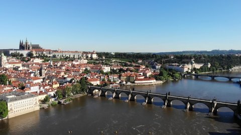 Aerial flyover over Vltava river in Praha, Czech Republic with a view of the Charles Bridge and the Prague Castle on a sunny morning