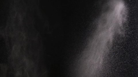 Slow motion. Water spray nozzle. White smoke isolated on black background with visible droplets. Water vapor jet from the humidifier. Spraying water droplets. Isolated water spray effect on the black