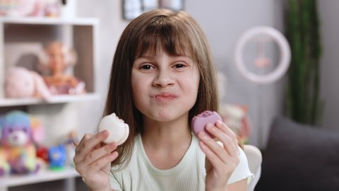 Hilarious school girl wants to eat two macarons at the same time, widely opens her mouth. Dessert, delicious. Tasty sweet color macaron. Feeling good, delicious