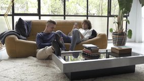 Young male gay couple relaxed on the sofa enjoying digital technology connected to social media with smartphones at home