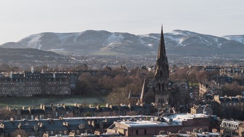 Establishing Aerial View Shot of Edinburgh UK, Scotland United Kingdom, high tower of the church and skyline with mountains