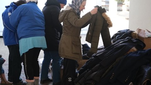 LVIV, UKRAINE - March 14, 2022: Refugees from Ukraine in a humanitarian center. People choose warm clothes donated by volunteers. Russian invasion of Ukraine. War in Ukraine