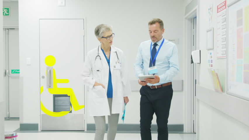 Senior woman doctor having a discussion in hospital hallway with medical staff. Pharmaceutical representative showing medical report on digital tablet about new medicine or therapy. Royalty-Free Stock Footage #1088219767