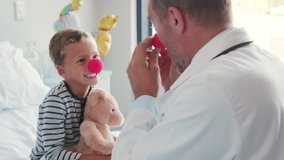 Smiling little boy wearing red nose and hugging doctor in hospital bed. Happy playful child playing to funny pediatrician at clinic. Kid joking during medical examination with physician, clown therapy - Powered by Shutterstock - Get 15% off with code: PIKWIZARD15