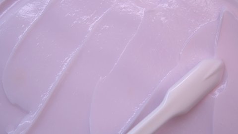 Texture of a pink soft cream.Cosmetic white brush smears the cream.Advertising a mask or face cream. The composition of care cosmetics.