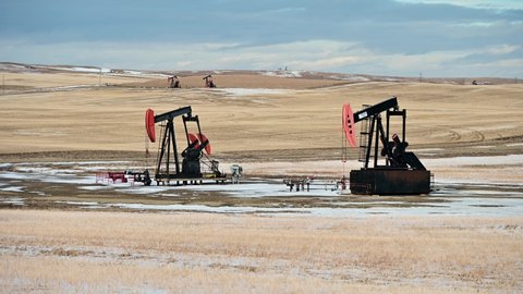 Milo, Alberta - March 12, 2022: Oil pump jacks in Alberta, Canada operating on a winter evening. 