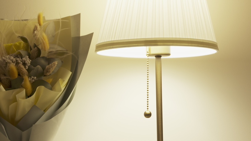 Console table with bouquet of flowers lit by a table lamp in the living room, apartment decoration background. High quality 4k footage