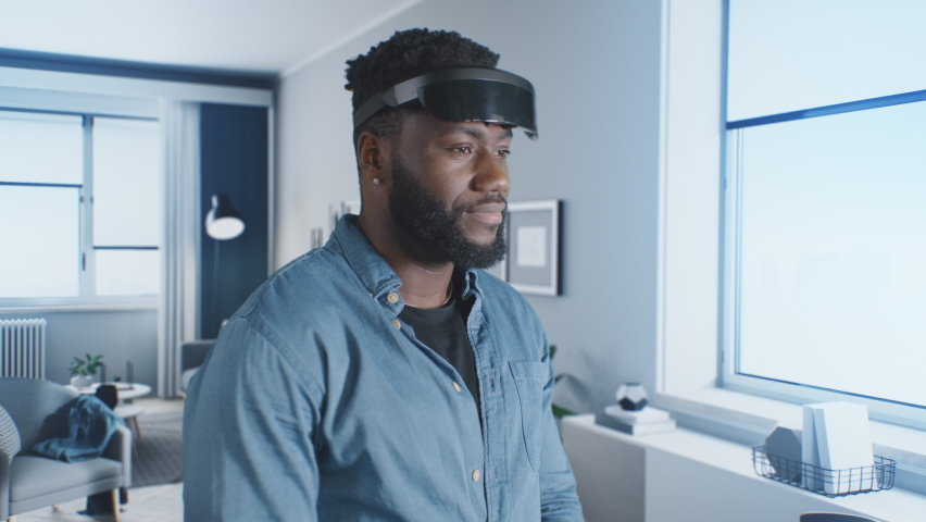 African American man putting on VR headset and looking around to the cyber world of the meta universe, in which other people communicate and dance. Royalty-Free Stock Footage #1088223715