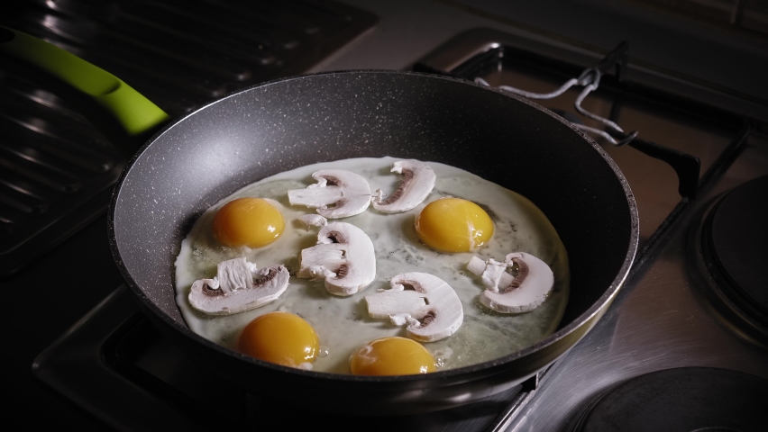 Eggs With Slices Of Mushrooms Cooking In A Pan, Adding Chopped Avocado Fruit. close up