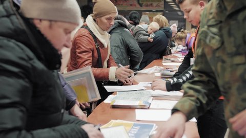 Chelm , Europe , Poland - 03 03 2022: Refugees from Ukraine. They fill out the documents at the refugee admission point. Mothers with babies are waiting in line. Poland, Chelm Hala MOSIR 2022.03.03.