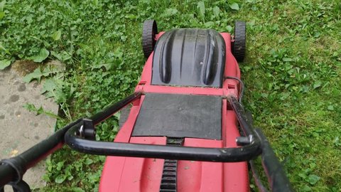 Electric lawn mower. Man in private yard with lawn mowers. Static shot. Gardening activity. Cutting grass with electric driven lawn mower in garden. mower machine. mowing the lawn.