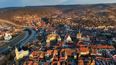 aerial view of historic medieval town of Sighisoara at sunset, aerial view of famous tourist destination in Romania, scenic unesco heritage site in Transylvania in winter. High quality 4k footage