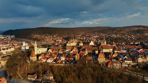 flying above historic medieval town of Sighisoara at sunset, aerial view of famous tourist destination in Romania, scenic unesco heritage site in Transylvania in winter. High quality 4k footage