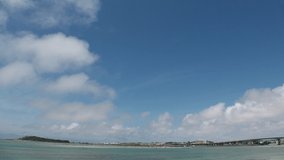TOMIGUSUKU, OKINAWA, JAPAN - AUGUST 2021 : View of Senaga island beach (Ocean or sea) and airplane in daytime. Clear blue summer sky and clouds. Holiday, vacation and resort concept video.
